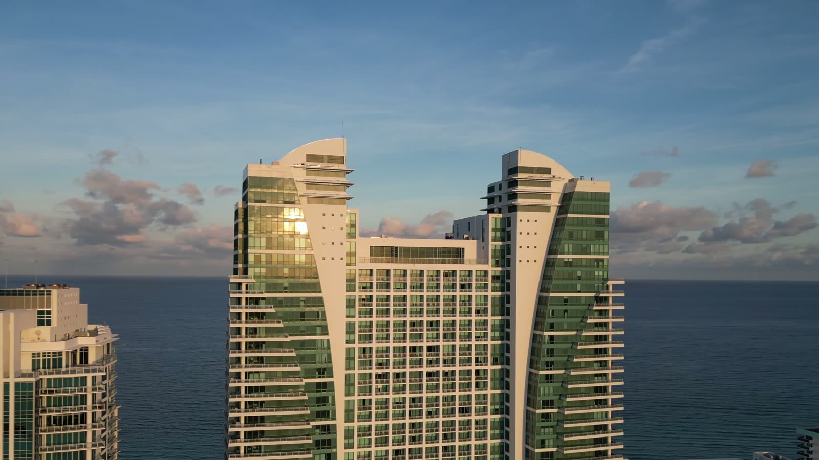 Two coastal high-rise towers photographed from the air at sunrise