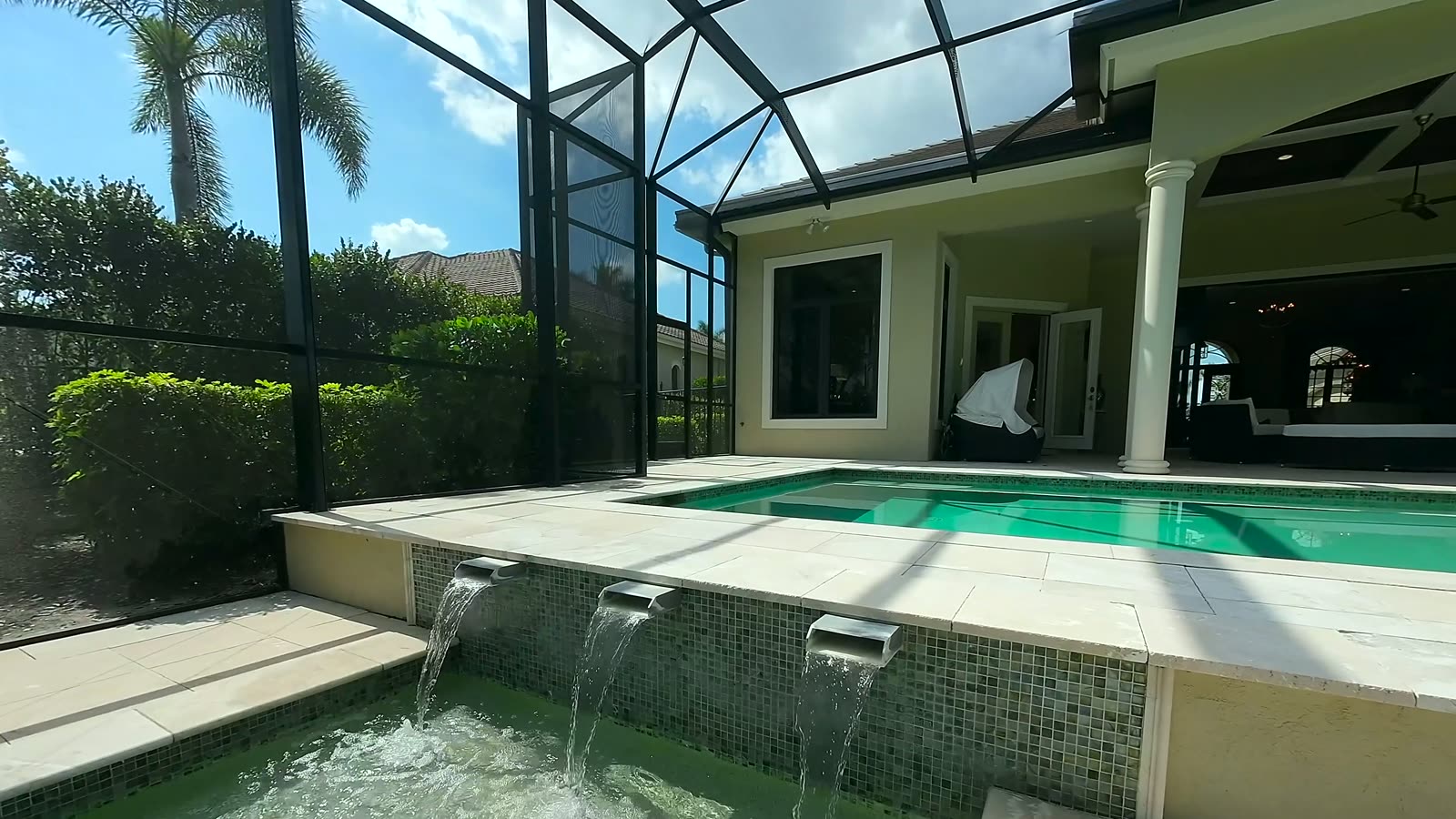 Screened pool enclosure with water feature at dusk